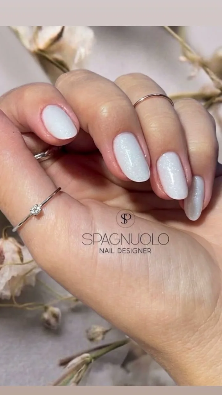 Unhas brancas peroladas em composição floral